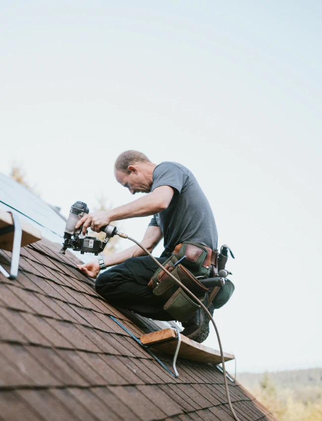 worker installing apshalt roof shingles